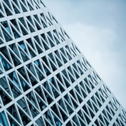 Detail shot of a modern skyscraper facade featuring a white, geometric lattice framework over glass windows.