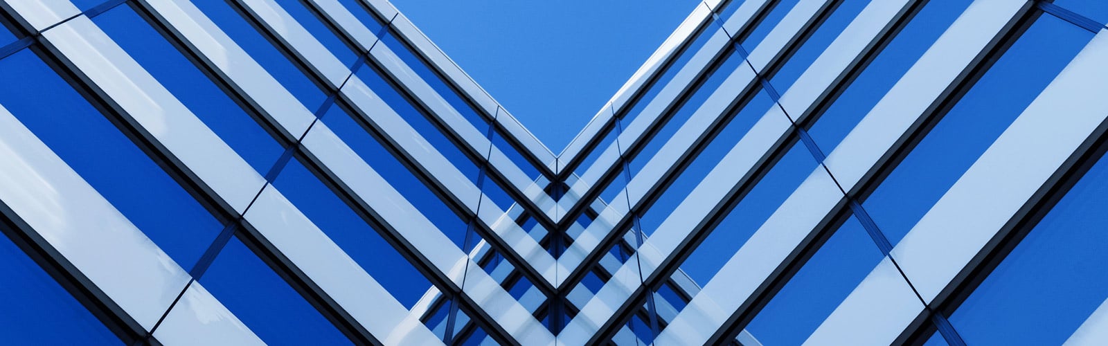 An abstract architectural photograph featuring symmetrical blue and white geometric lines converging in a V-shape against a clear blue sky, representing stability and structure.