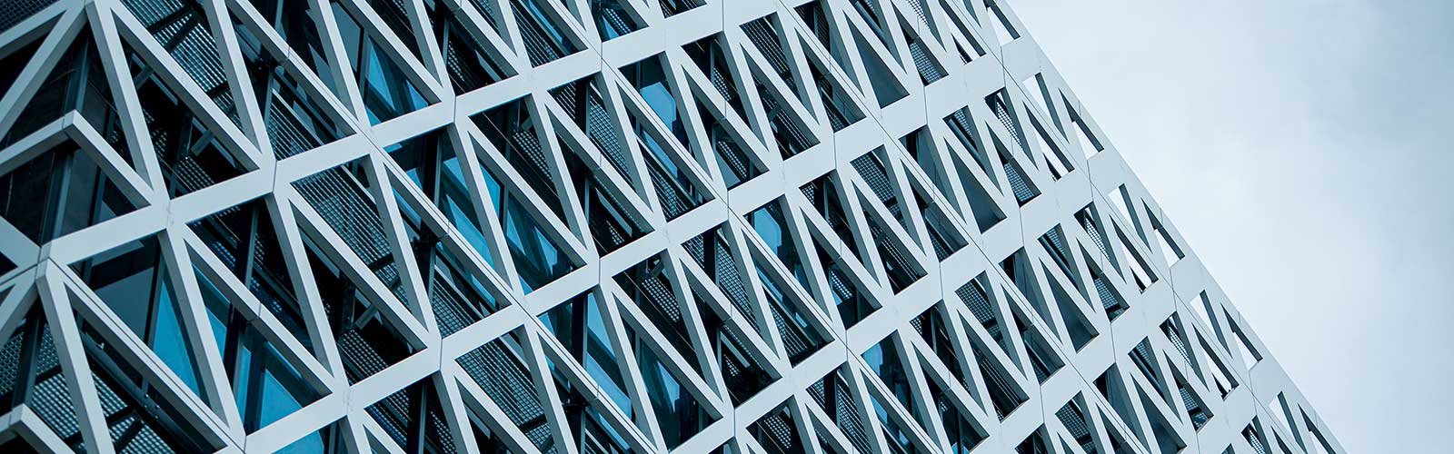 Detail shot of a modern skyscraper facade featuring a white, geometric lattice framework over glass windows.