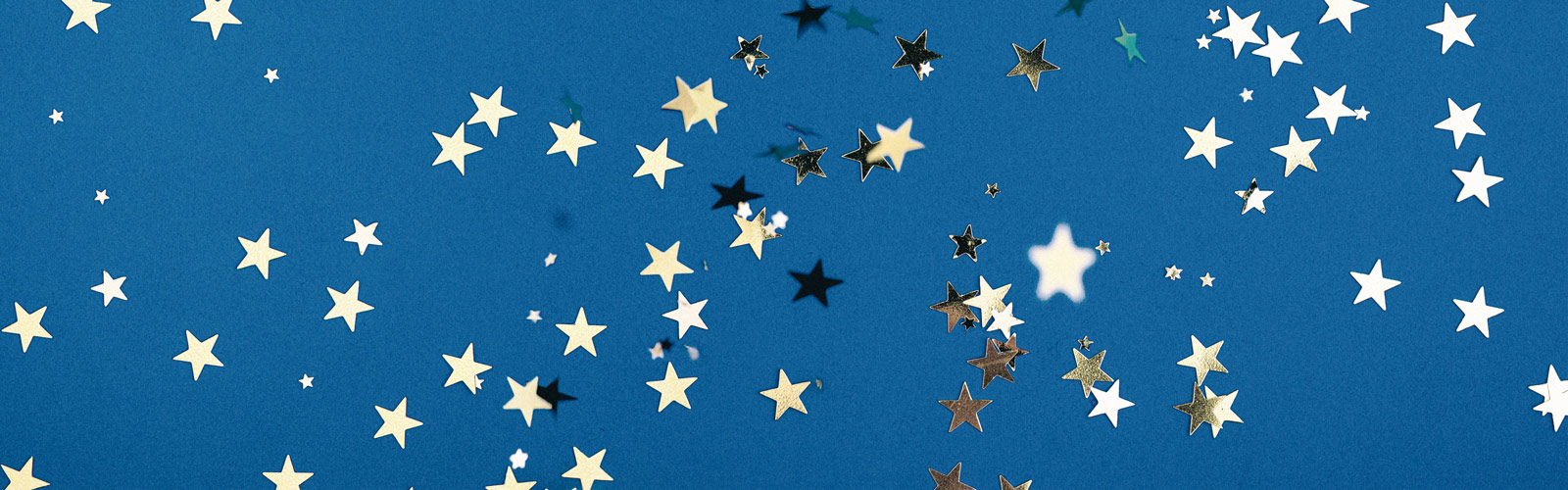 A celebratory image of gold star-shaped confetti on a solid blue background.