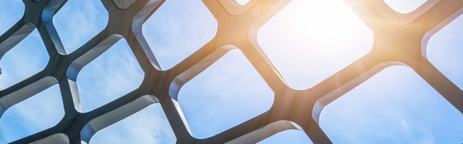A modern, geometric architectural roof against a bright, sunny sky